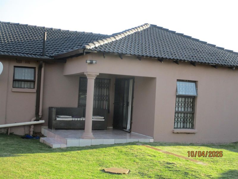 A rear view of the house featuring a covered patio area with tiled flooring, security gates, and a tiled roof.