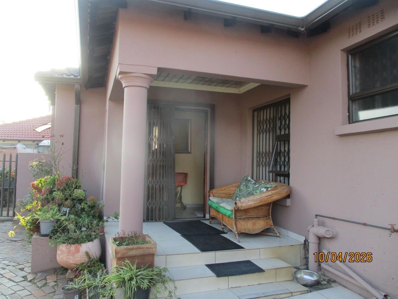 A covered entrance patio featuring tiled flooring, a structural column, and security gates at the main doorway.