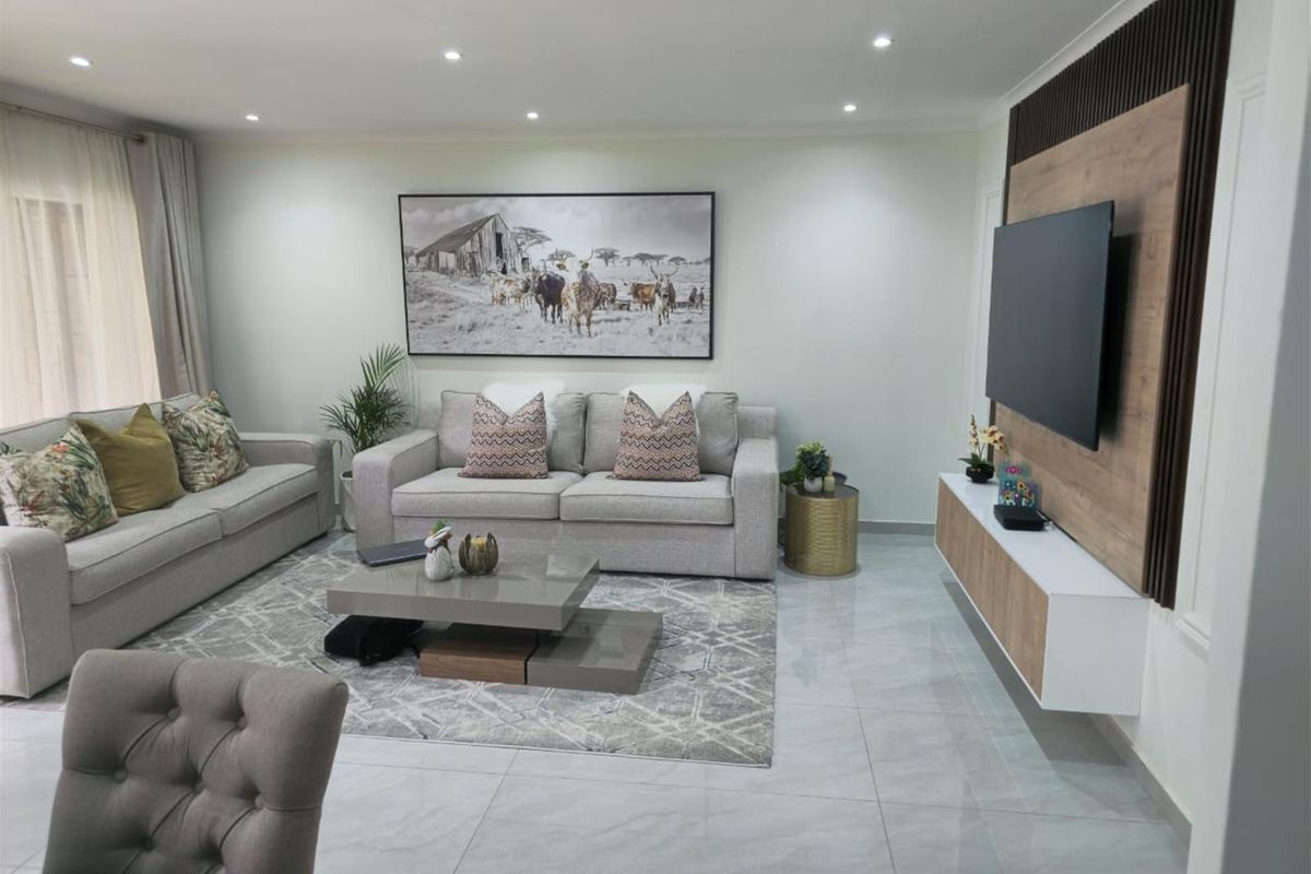 Modern living room featuring polished tiled flooring, recessed downlighting, and a custom built-in media wall with decorative timber slat paneling.