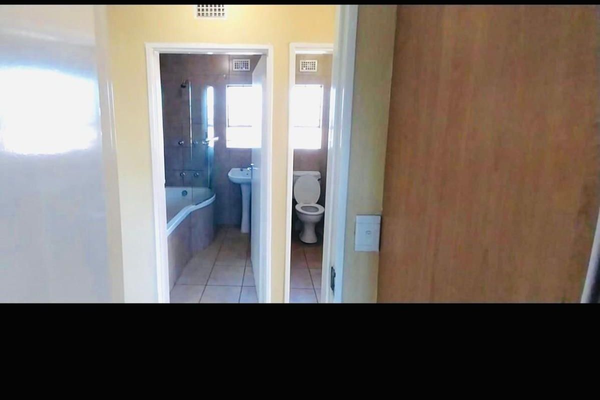 A functional bathroom layout featuring a separate bathtub area and toilet, with tiled flooring and standard sanitary fixtures.