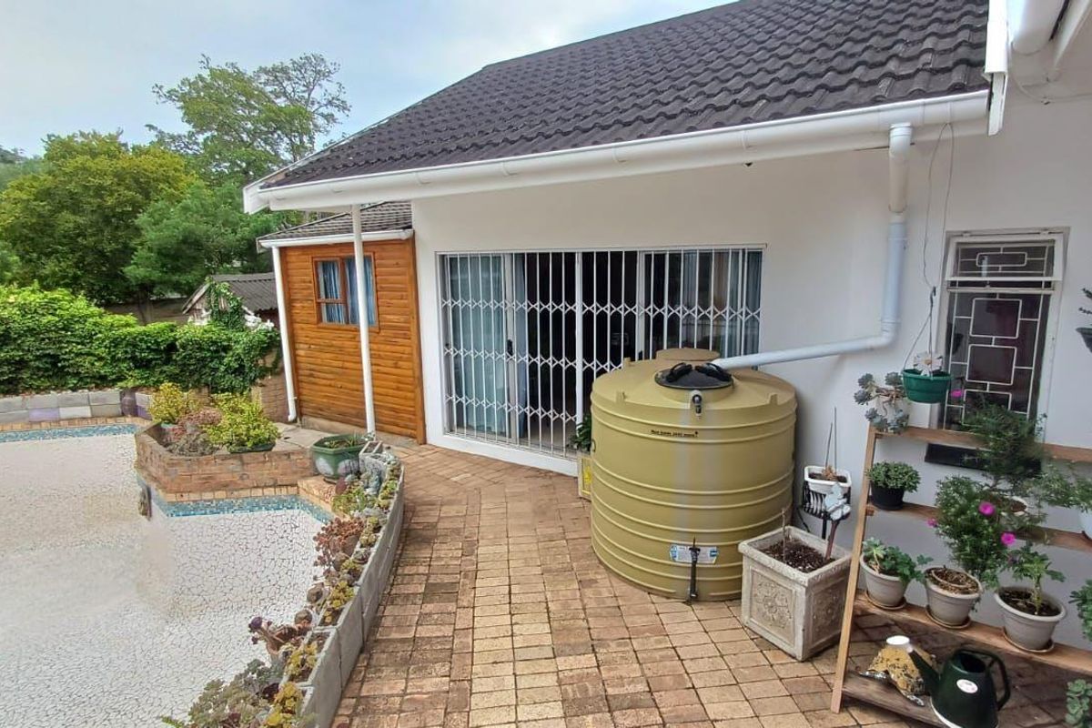 Rear exterior view featuring a paved patio, rainwater tank, and a swimming pool with visible maintenance requirements.