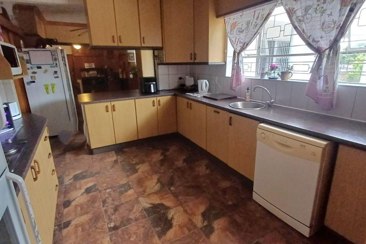 A functional kitchen featuring dated laminate cabinetry, tiled flooring, and a stainless steel sink, offering significant potential for a modern renovation.