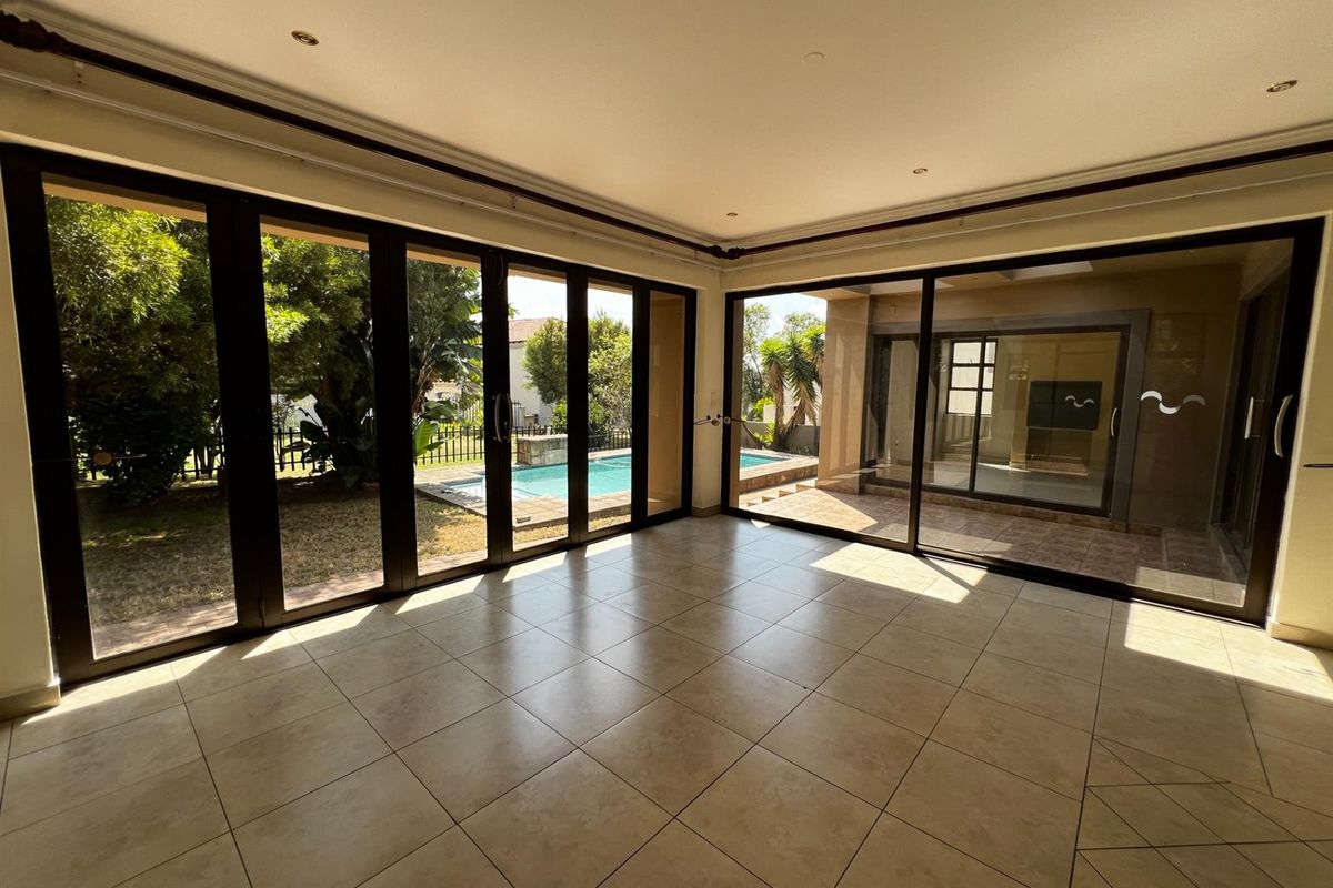 Bright living area featuring large floor-to-ceiling glass sliding doors that provide seamless access to the outdoor patio and swimming pool area.