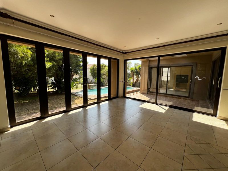 Bright living area featuring large floor-to-ceiling glass sliding doors that provide seamless access to the outdoor patio and swimming pool area.