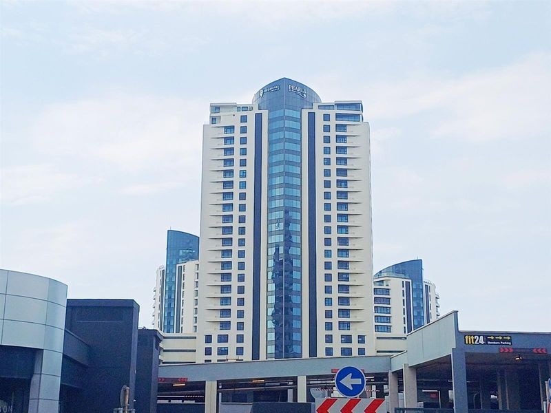 A view of the high-rise apartment building facade featuring modern architectural design, glass elements, and integrated parking facilities.