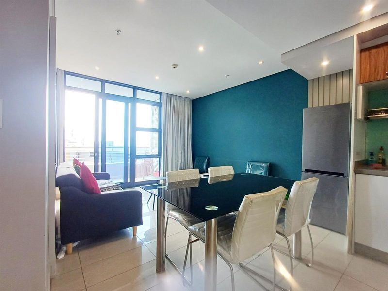 Open-plan living and dining area featuring tiled floors, recessed lighting, and direct access to a private balcony through large sliding glass doors.
