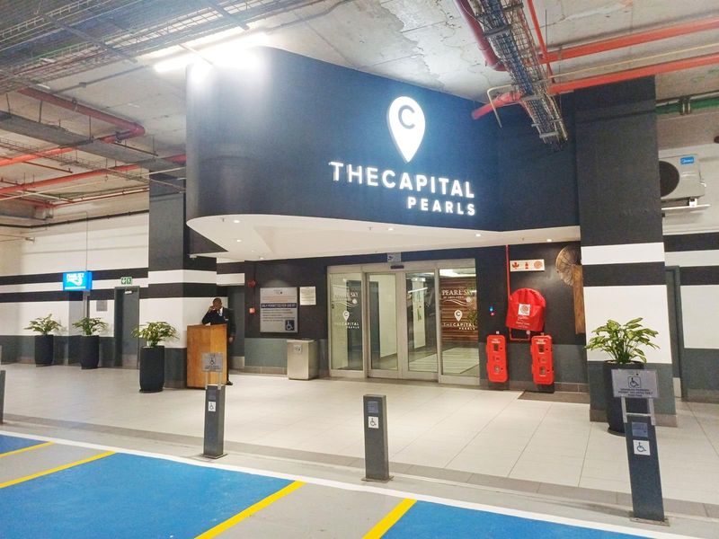 The entrance lobby of The Capital Pearls, featuring modern tiled flooring, secure glass sliding doors, and clearly marked fire safety equipment.