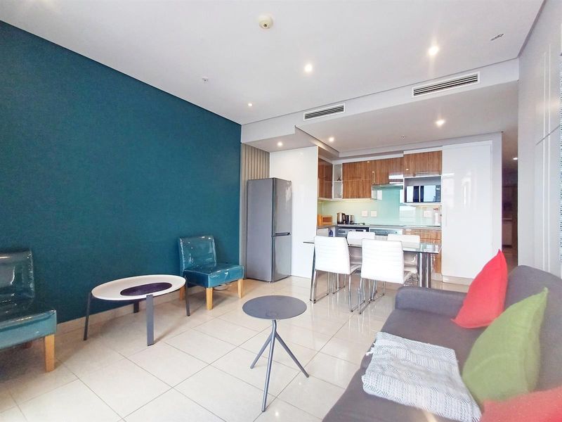 Modern open-plan living and kitchen area featuring tiled floors, recessed lighting, ducted air conditioning, and contemporary cabinetry with integrated appliances.