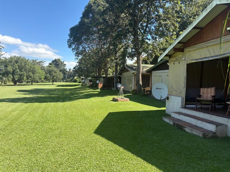 A view of the rear exterior of the holiday accommodation units, featuring a large manicured lawn and private deck areas.