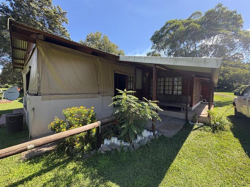 Rear view of a rustic holiday cabin featuring a covered patio area, timber wall cladding, and durable canvas side panels.