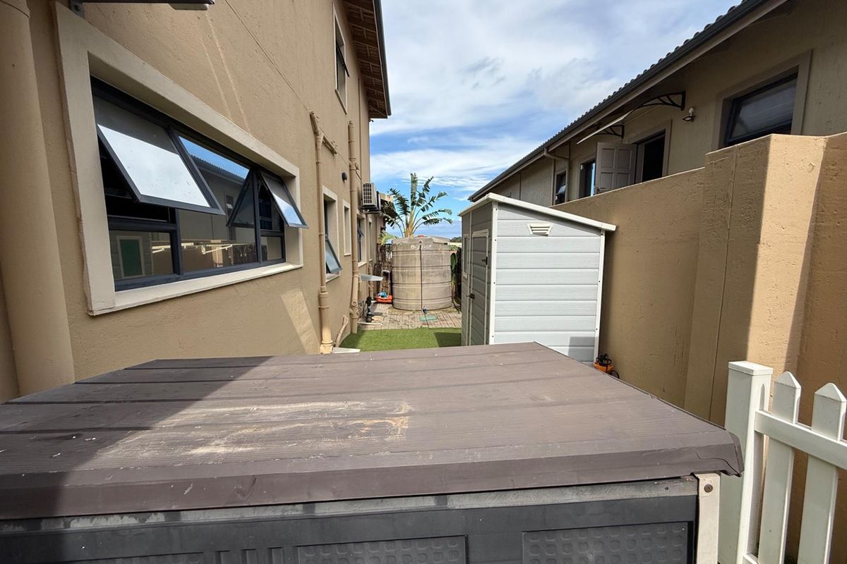 A side passage area between two residential buildings featuring a water storage tank, paved pathway, and boundary wall.
