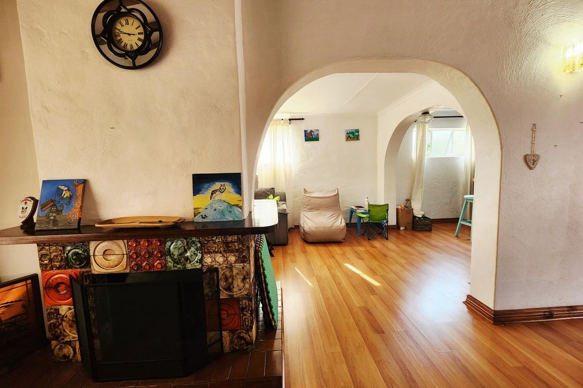 Living area featuring a distinctive tiled fireplace with a mantelpiece, arched architectural transitions, and warm-toned laminate flooring throughout the open space.
