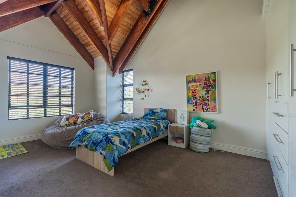 Spacious bedroom featuring high vaulted timber ceilings, neutral carpeting, and built-in cabinetry, offering a bright and airy atmosphere.