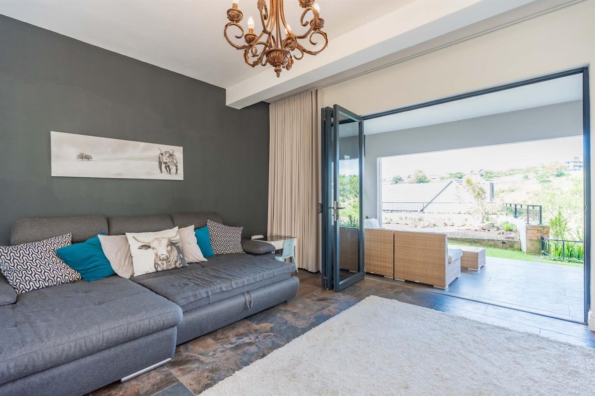 A modern living room featuring dark accent walls, tiled flooring, and large bi-fold doors that open onto a covered patio area.