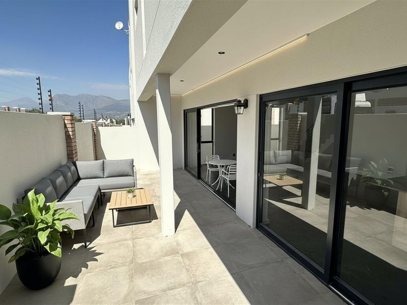 A modern covered patio featuring large format floor tiles, recessed lighting, and expansive sliding glass doors providing seamless indoor-outdoor flow.
