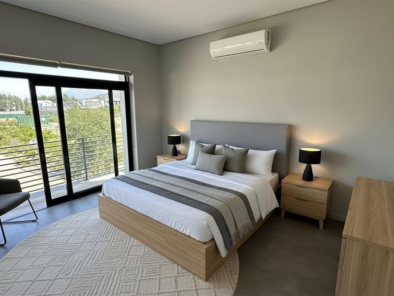 A modern, well-maintained bedroom featuring large sliding glass doors leading to a balcony, neutral finishes, and a wall-mounted air conditioning unit.