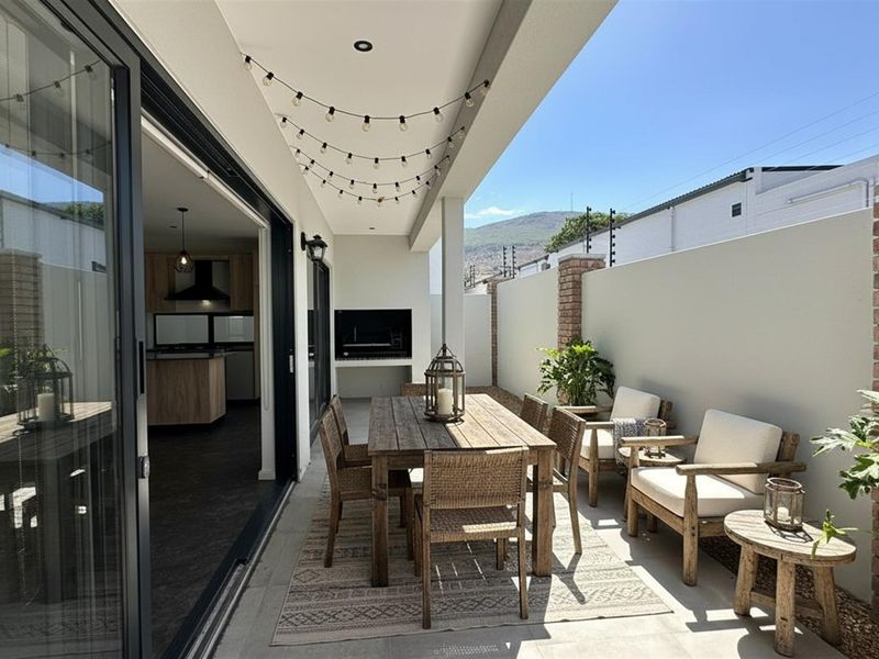 A covered patio featuring a built-in braai, tiled flooring, and seamless flow from the interior living space, ideal for outdoor entertaining.