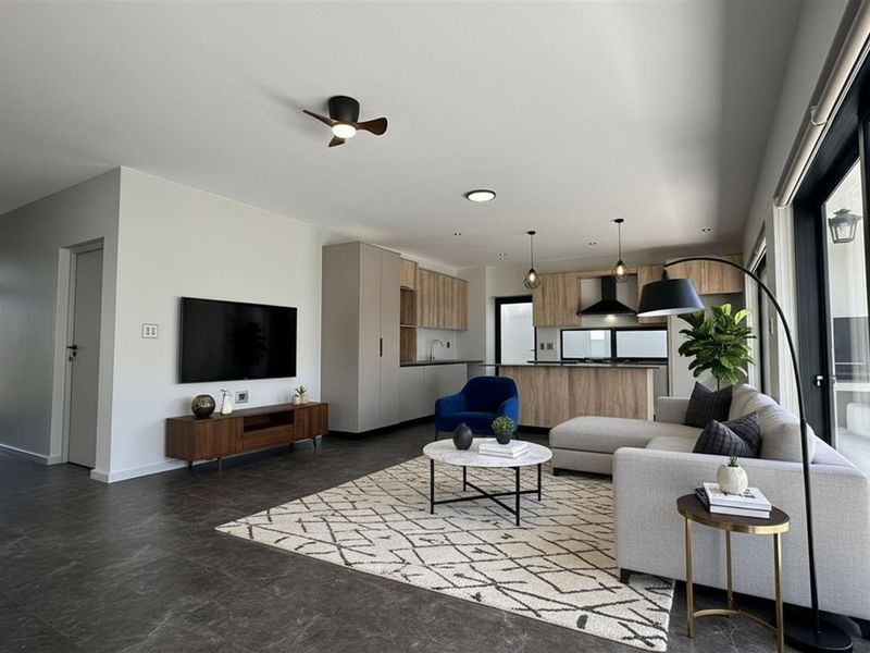 Modern open-plan living area featuring a sleek kitchen with wood-tone cabinetry, integrated appliances, and large sliding glass doors leading to the patio.