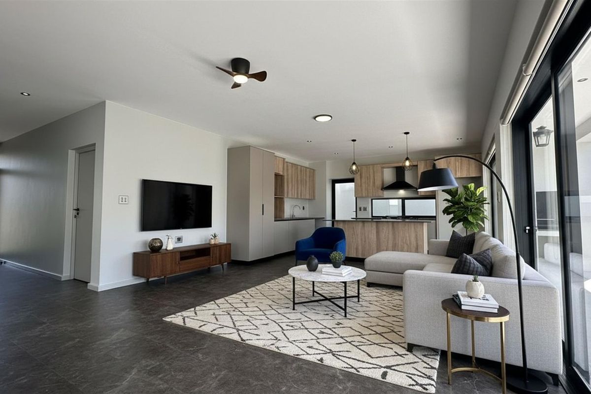 Modern open-plan living area featuring a sleek kitchen with wood-tone cabinetry, integrated appliances, and large sliding glass doors leading to the patio.