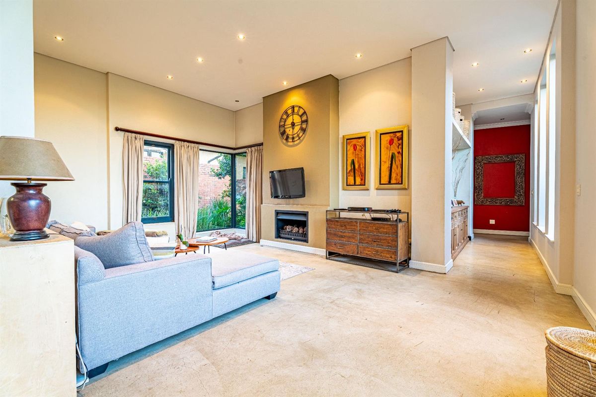 Spacious living room featuring a built-in fireplace, recessed downlighting, and large windows overlooking the garden, creating a bright and inviting atmosphere.