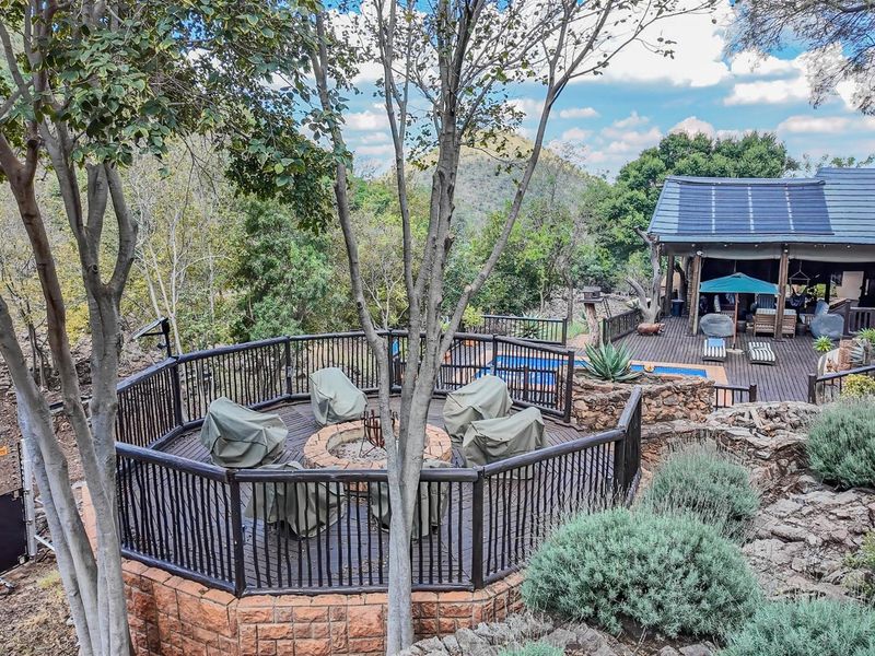 Elevated outdoor entertainment area featuring a circular wooden deck with a built-in fire pit, stone masonry base, and scenic natural surroundings.