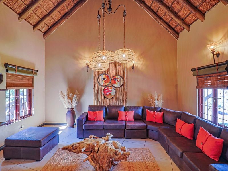 Spacious living room featuring a high vaulted thatched ceiling with exposed timber rafters and large windows, creating a warm and inviting atmosphere.