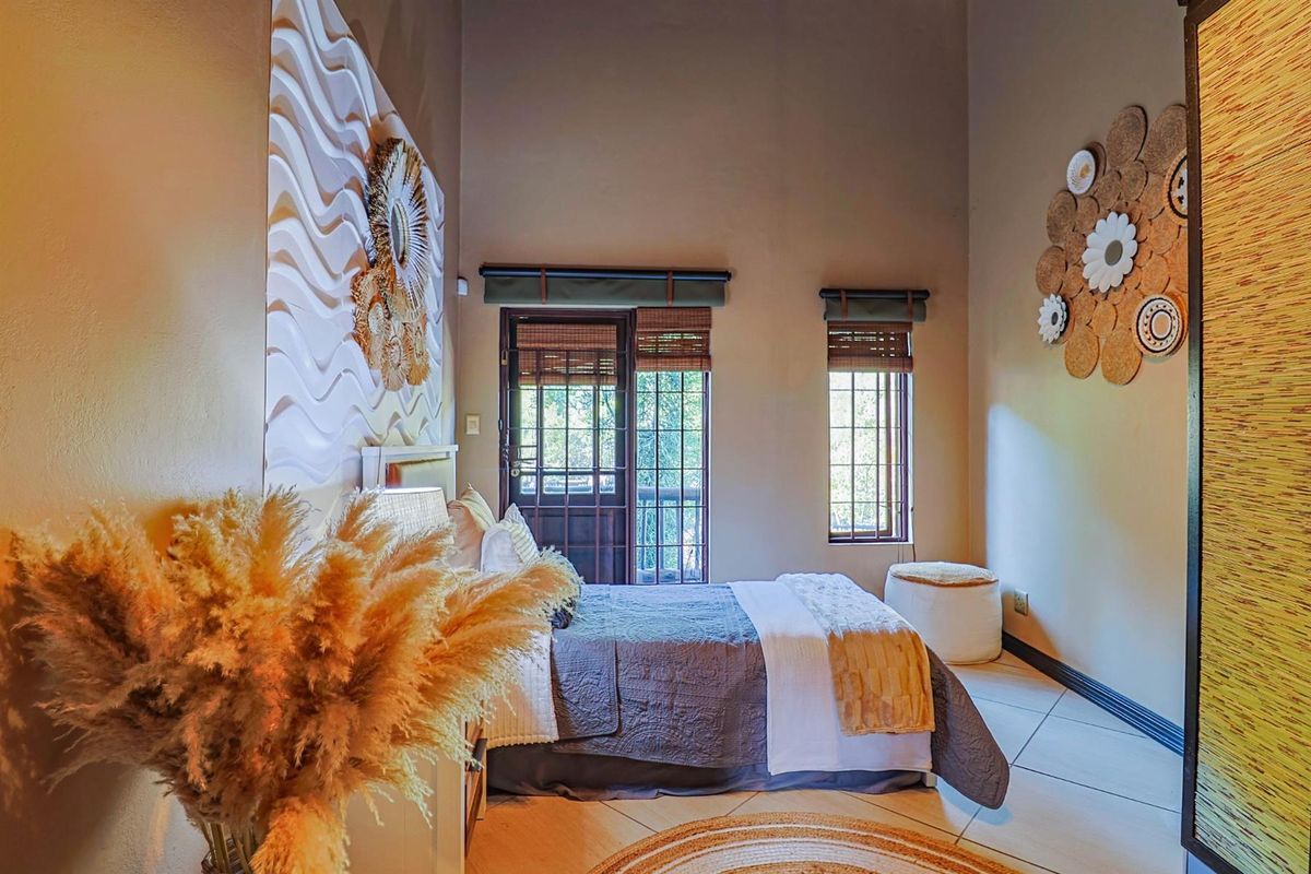 A well-lit bedroom featuring high ceilings, tiled flooring, and direct access to an outdoor area through a secure door.
