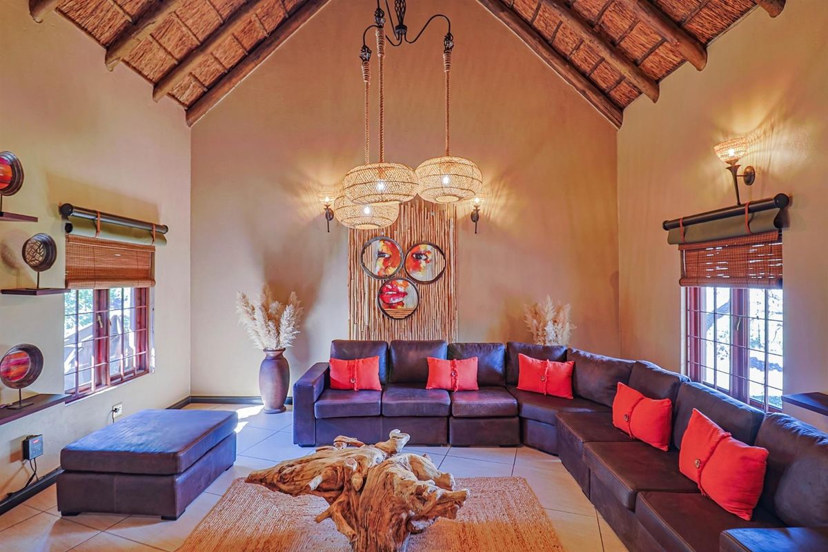Spacious living room featuring a high vaulted thatched ceiling with exposed timber rafters and large windows, creating a warm and inviting atmosphere.