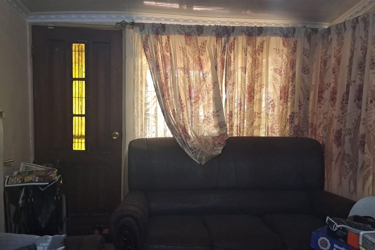 A living room area featuring a solid timber entrance door with glass inserts and decorative ceiling cornicing.