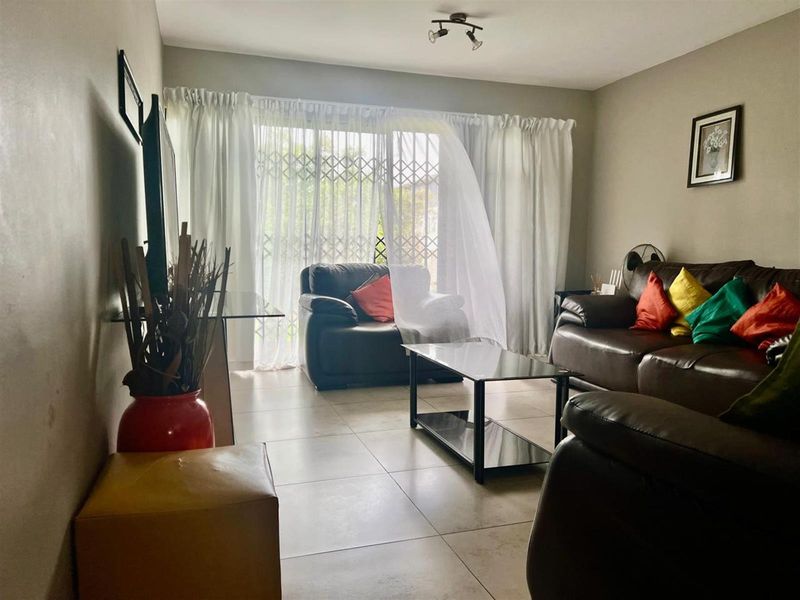 A living room featuring tiled flooring and a sliding glass door with a security gate, providing access to the exterior.