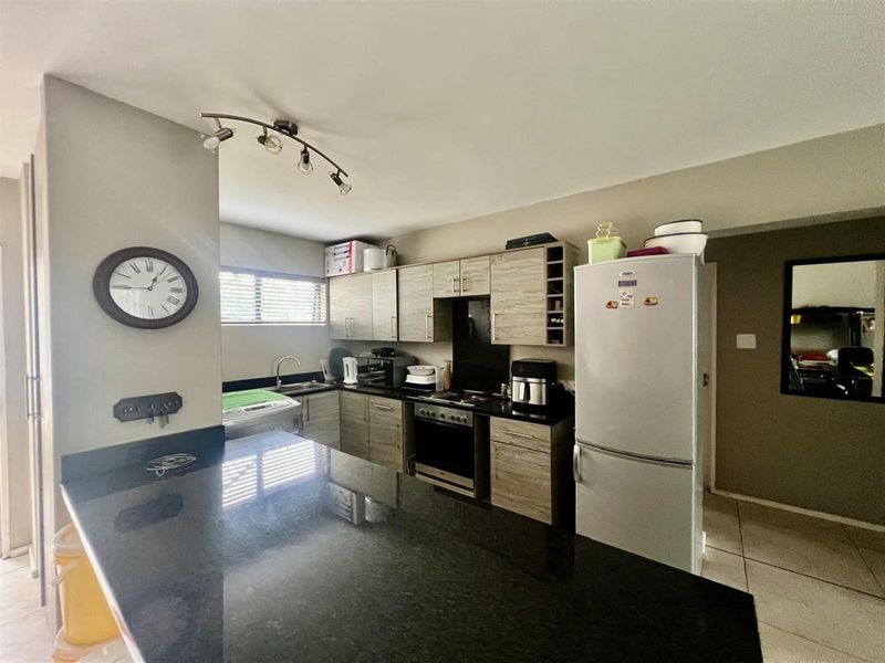 A functional kitchen featuring wood-finish cabinetry, granite countertops, a breakfast bar, and integrated cooking appliances, offering a practical layout for daily use.