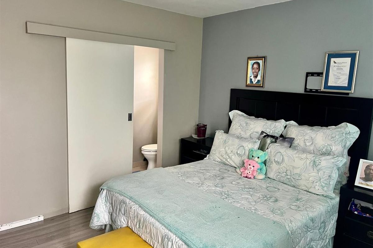 A bedroom featuring laminate flooring and a sliding door providing access to an en-suite toilet.