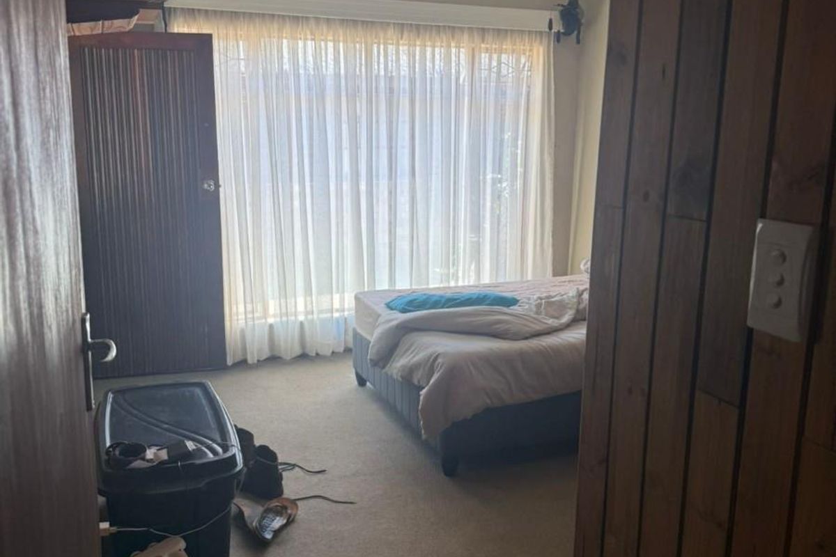 A bedroom featuring carpet flooring, a ceiling fan, and built-in cupboard storage, viewed from the doorway.