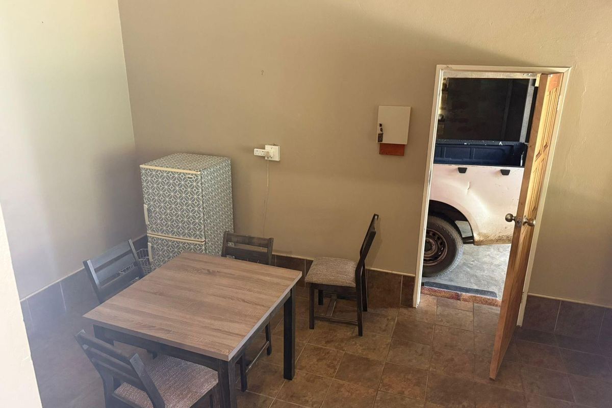 A simple interior space featuring tiled flooring and a wooden door leading to an exterior area.