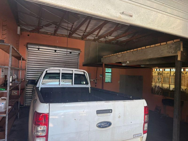 A functional garage space featuring a roller shutter door, exposed roof trusses, and a built-in mezzanine storage platform.