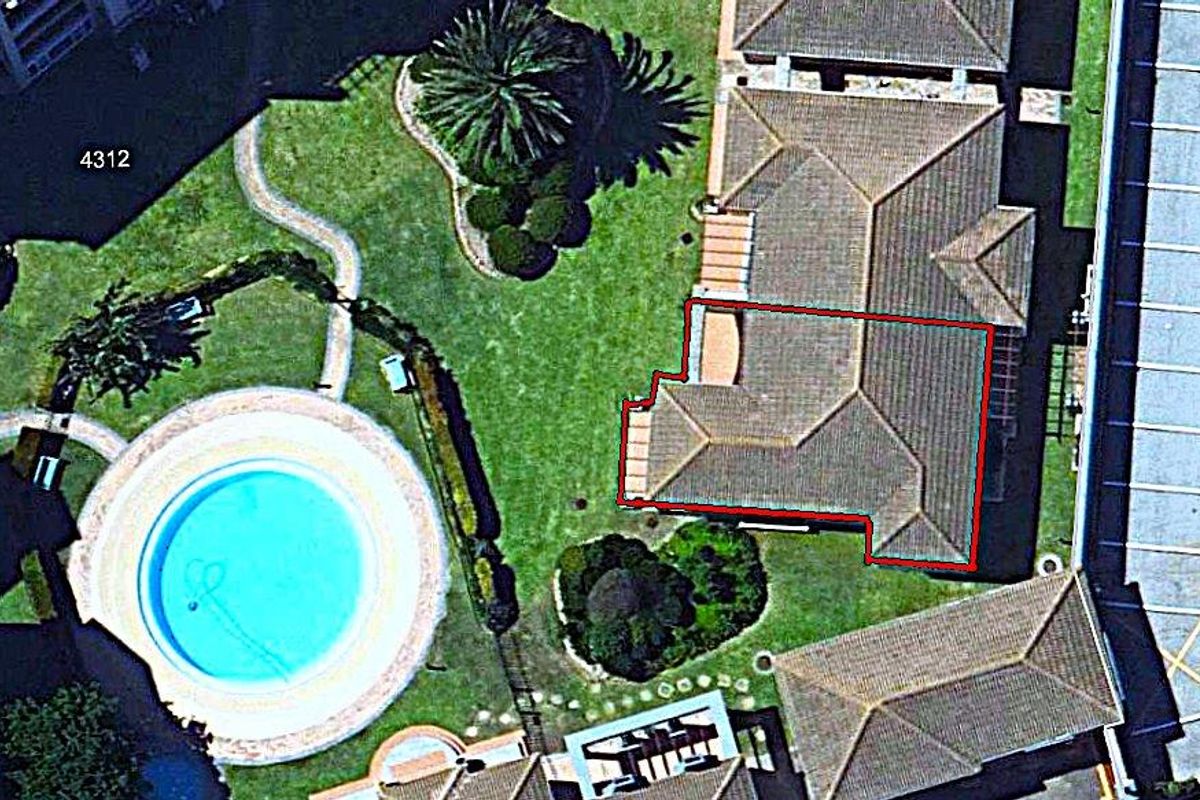 Aerial view of the property complex featuring a swimming pool, landscaped garden areas, and tiled roof structures.