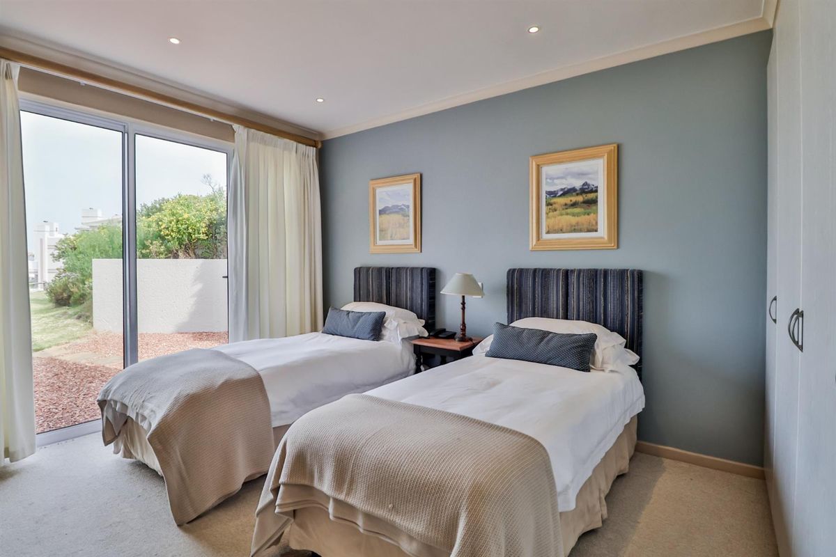 A well-maintained bedroom featuring neutral carpeting, built-in cupboards, and large sliding glass doors providing direct access to an outdoor patio area.