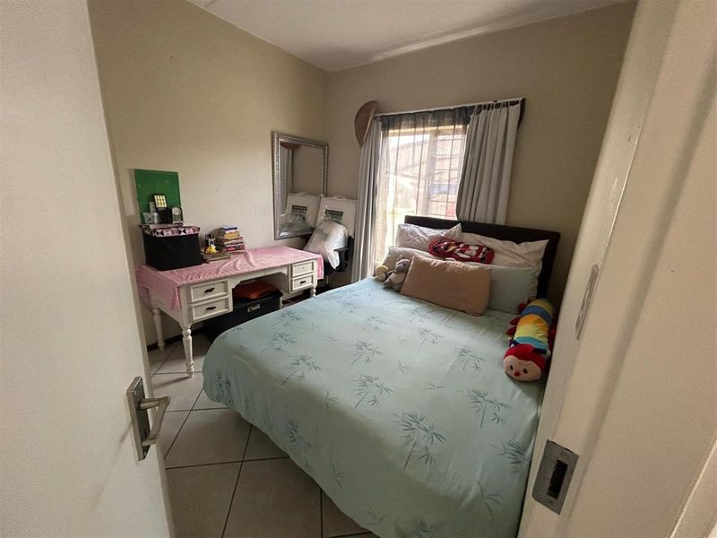 A compact bedroom featuring tiled flooring and a window with curtain rails, providing a functional space for a single or double bed.