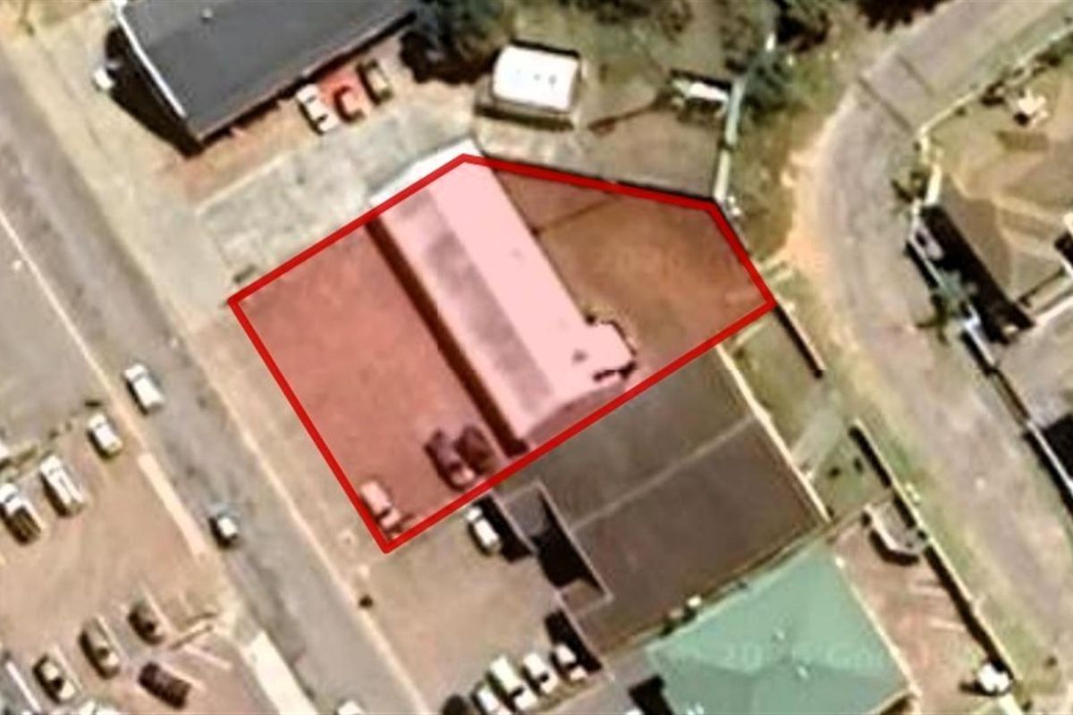 Aerial view of the commercial property site, highlighting the building footprint and surrounding paved area within the outlined boundary.