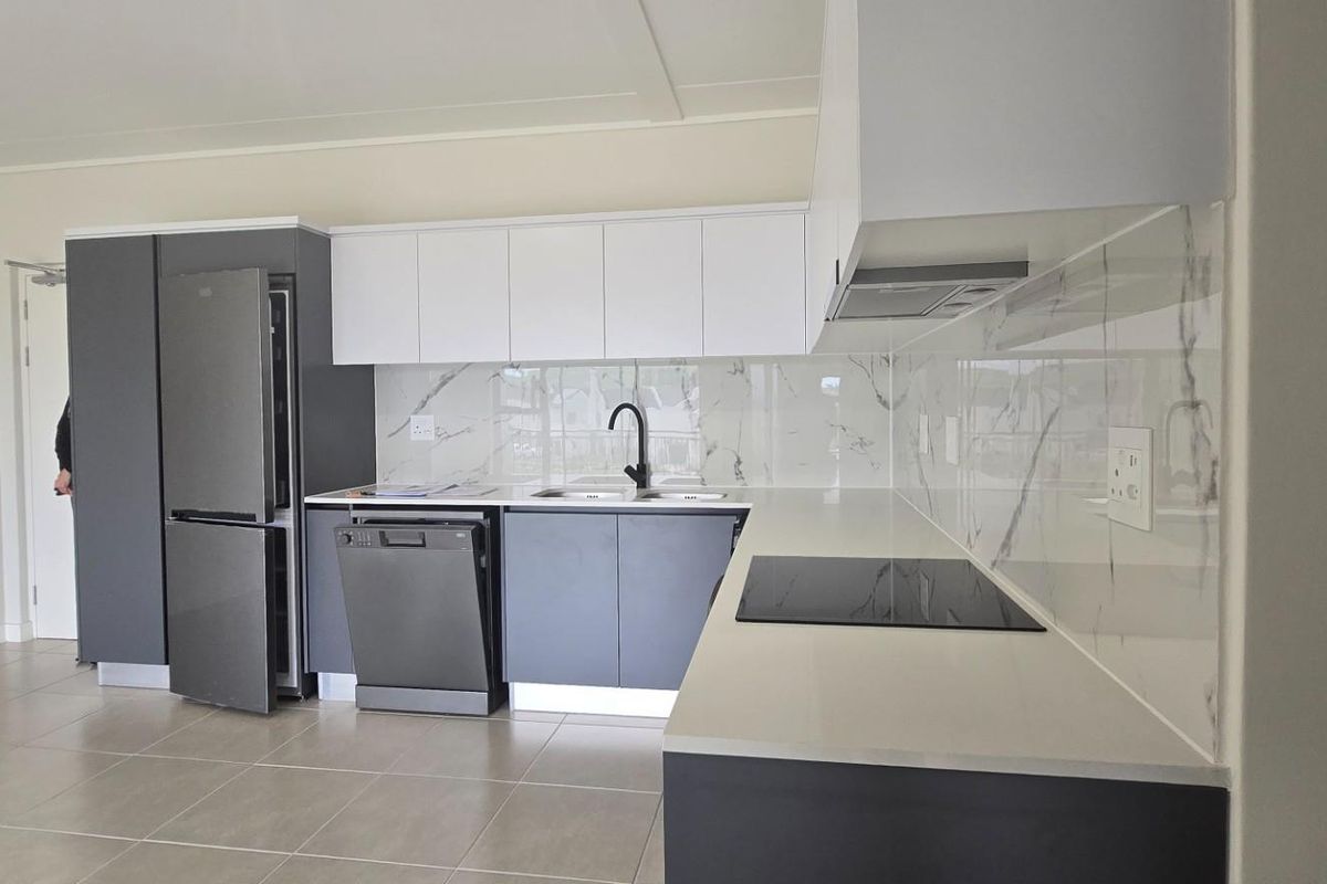Modern kitchen featuring sleek grey and white cabinetry, stone countertops, marble-look splashback, integrated hob, and high-quality finishes throughout.