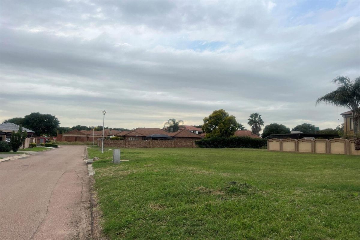 A vacant residential plot featuring a level grassed surface, situated in a developed neighbourhood with established boundary walls and street access.