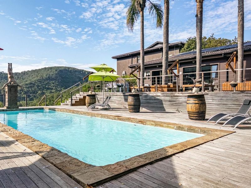 Spacious outdoor pool area featuring a large swimming pool, extensive timber decking, and elevated views of the surrounding landscape.