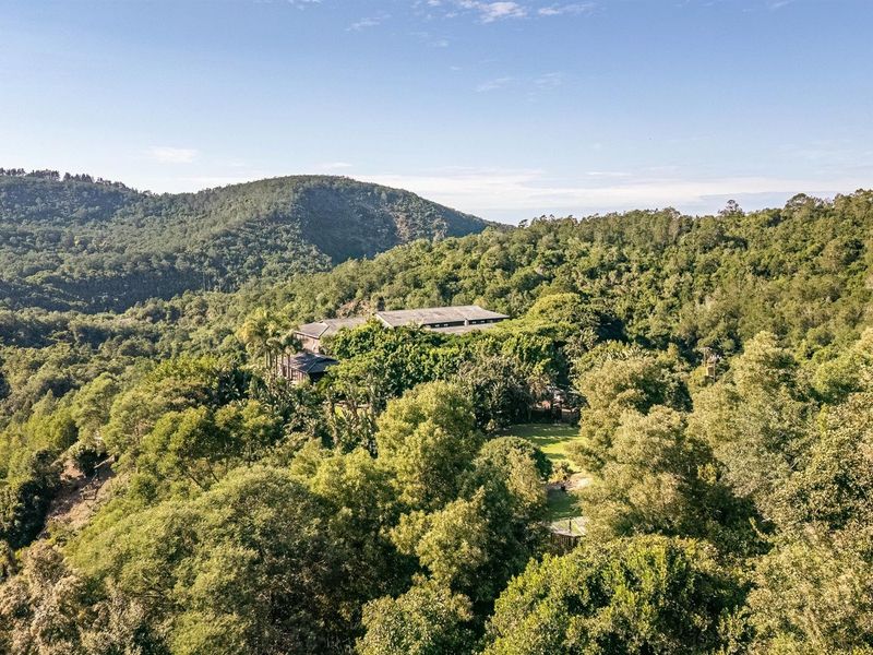 An aerial view of the property nestled within a lush, forested landscape, showcasing its secluded and natural setting.