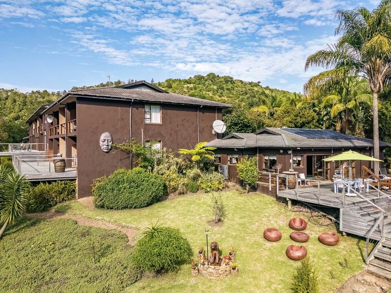 Aerial view of a multi-level residential property featuring timber decking, landscaped gardens, and solar panels on the roof.