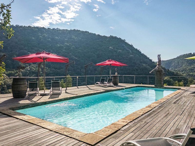 Outdoor swimming pool area featuring a wooden deck, stone coping, and panoramic mountain views.