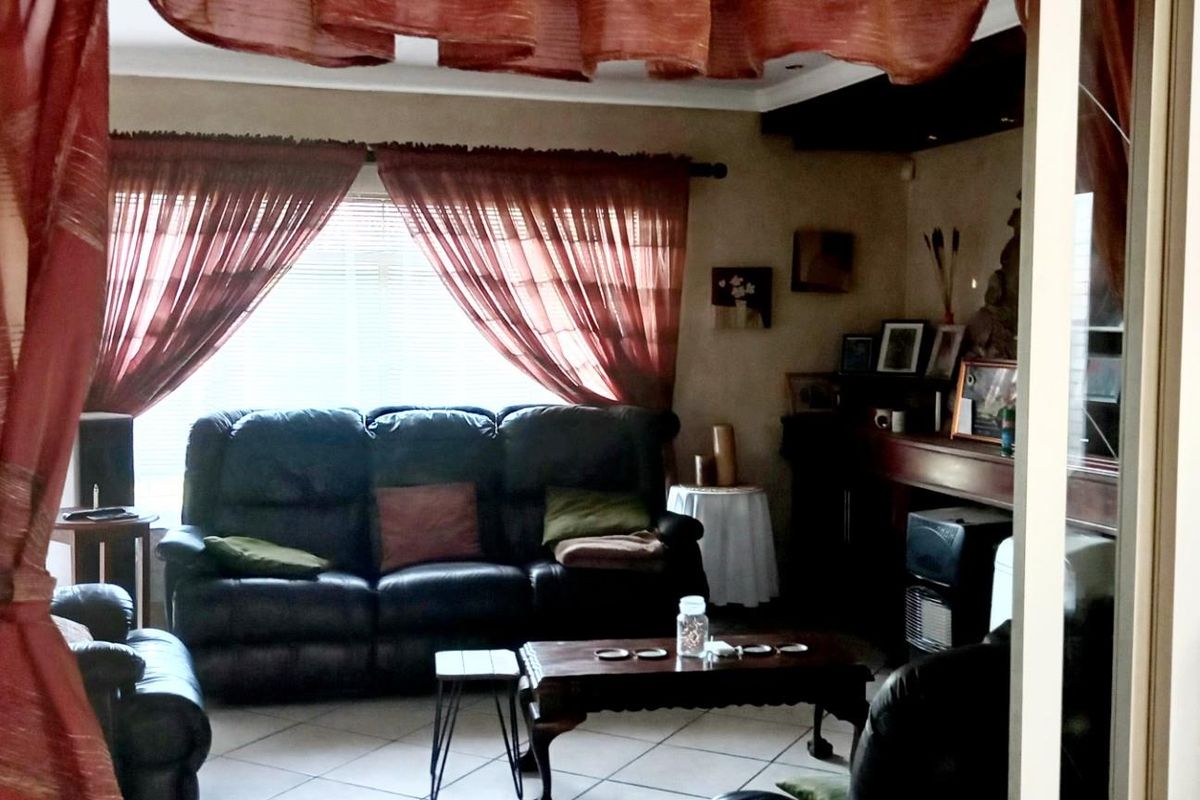 A comfortable living room featuring tiled flooring and a built-in fireplace, viewed through a doorway with decorative curtains.