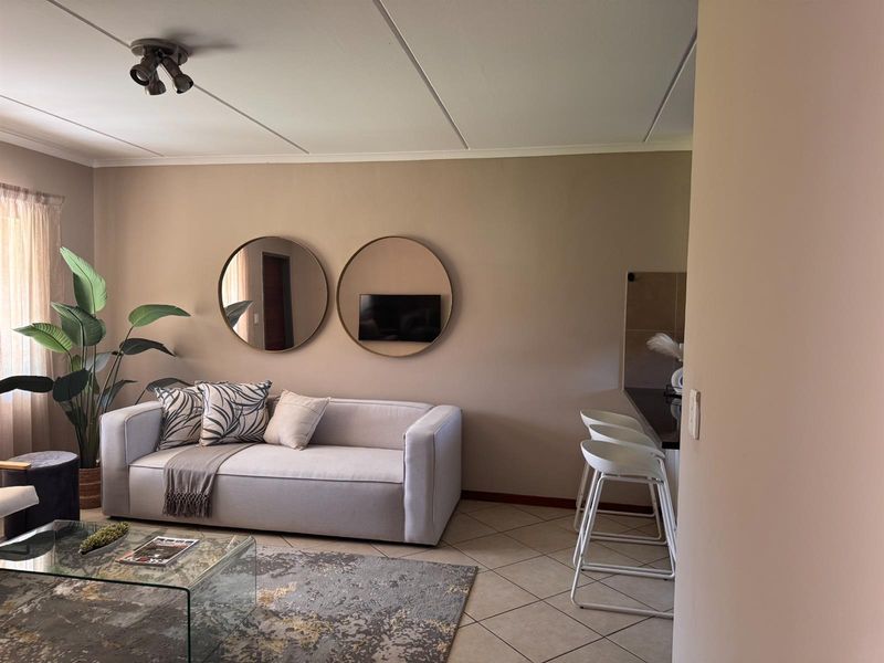 An open-plan living area featuring tiled flooring, neutral wall tones, and a breakfast bar counter, creating a functional and cohesive living space.