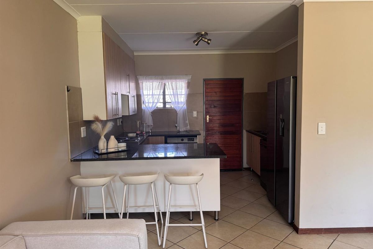 A functional kitchen featuring granite countertops, laminate cabinetry, a breakfast bar, and tiled flooring, providing a practical layout for daily use.