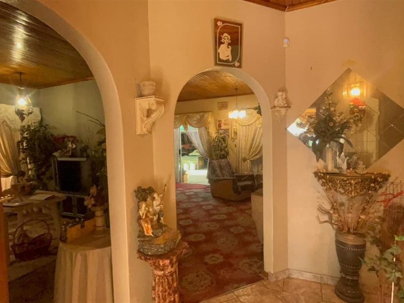 Entrance foyer featuring arched doorways leading into living areas, finished with timber ceilings and tiled flooring.