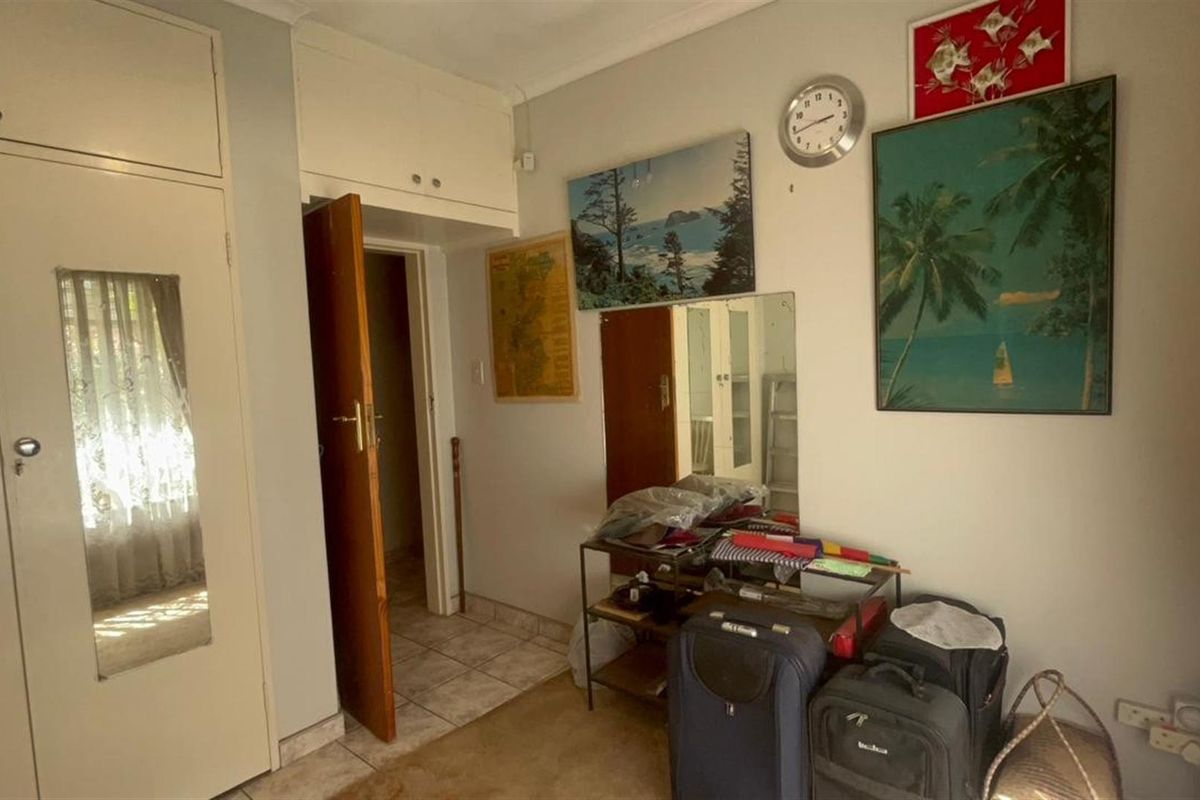 A bedroom featuring built-in cupboards and tiled flooring, providing functional storage and a neutral base for interior updates.